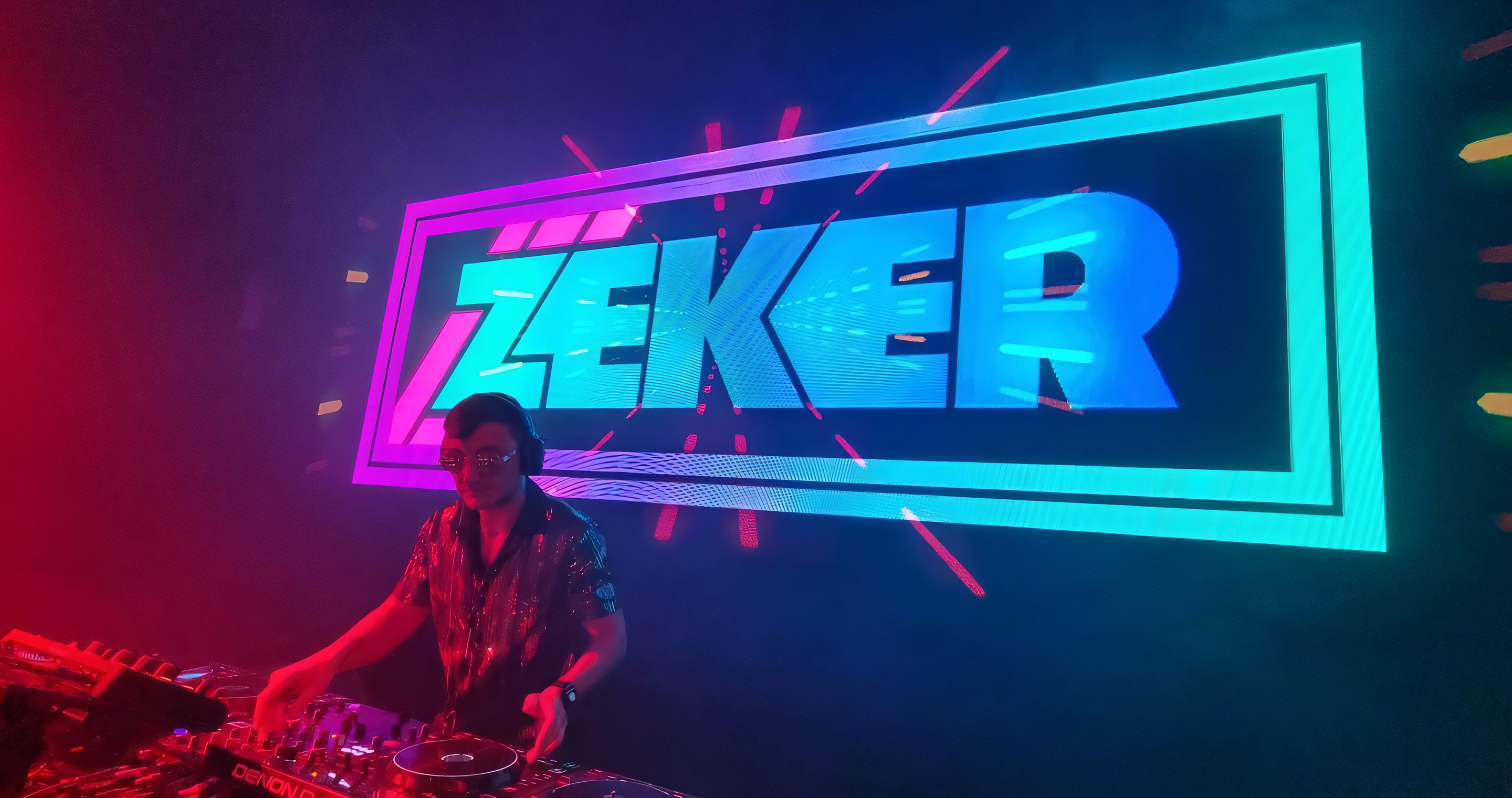Zeker DJing on the decks with logo projected behind him